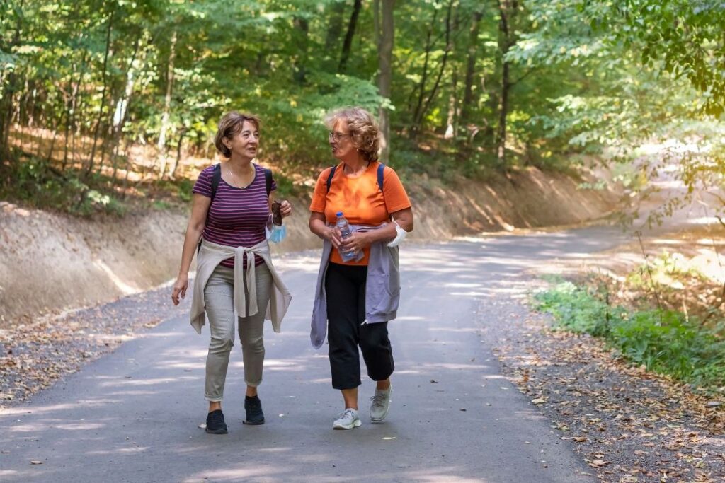 Two female friends going for a walk in the park talking about their ideal life.