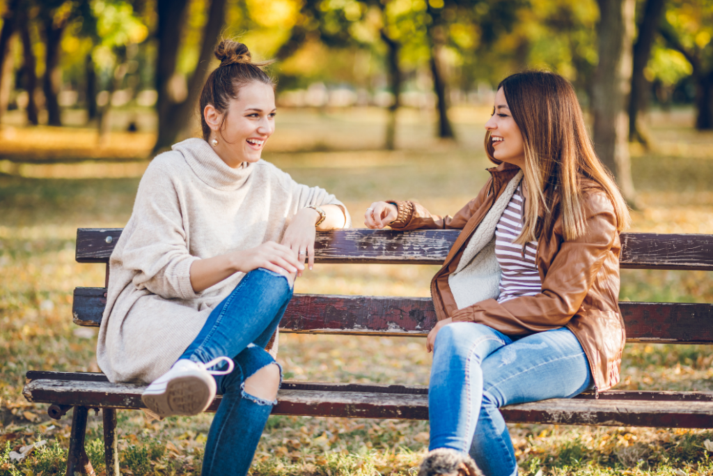 Two women sitting on a park bench chatting