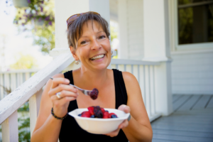 woman sitting on her deck eating a bowel full of berries