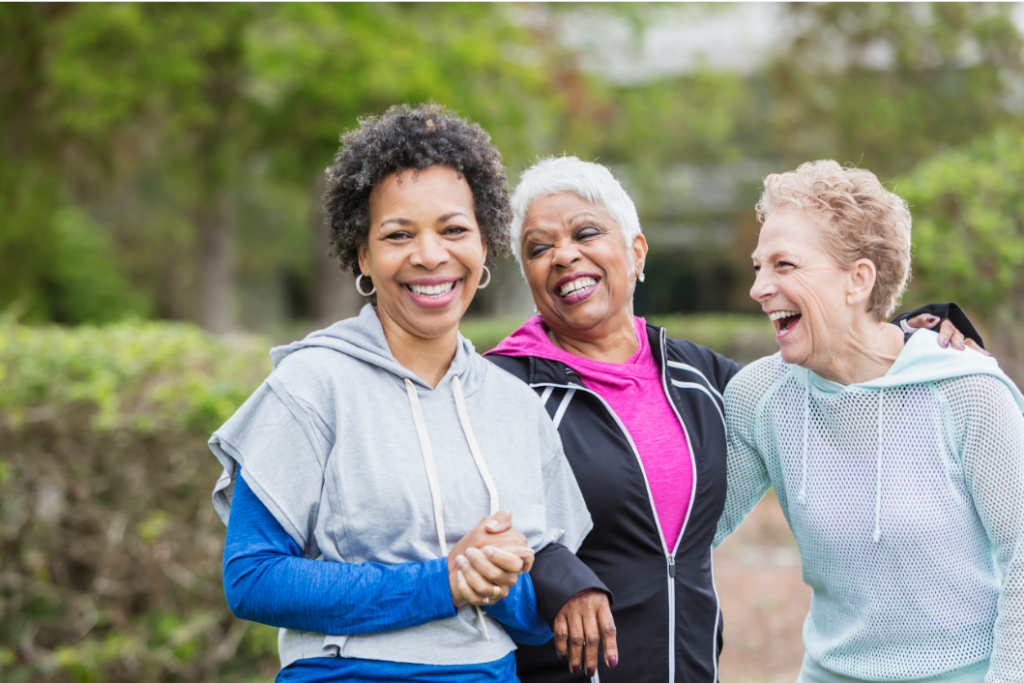 3 middle aged women embracing social connection and physical activity in the park