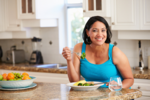 woman sitting in kitchen eating veggies