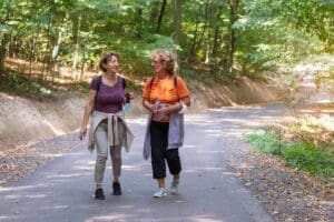 Two female friends going for a walk in the park talking about their ideal life.