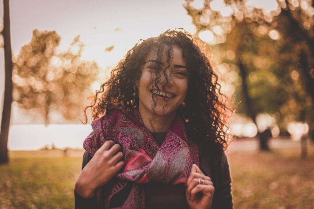 Woman with curly hair outside with a purple scarf