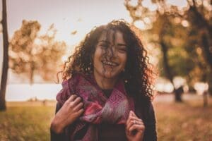 Woman with curly hair outside with a purple scarf