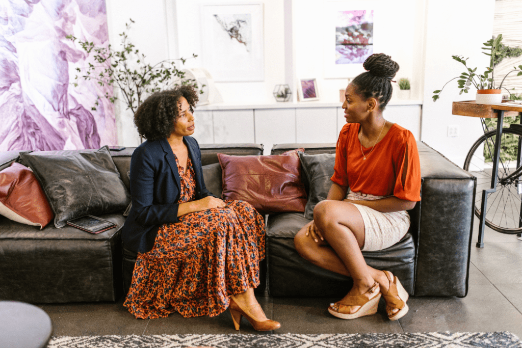 Two women sitting on a couch communicating