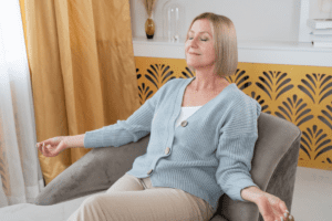 Woman sitting on couch doing breathing exercises